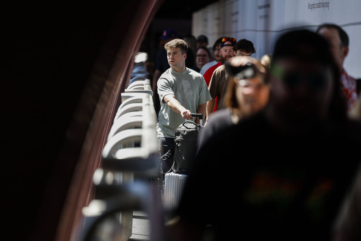 Travelers walk by new displays aimed at promoting tourism on their way to the rideshare area at ...