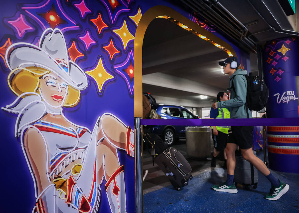 People pass new displays aimed at promoting tourism at the rideshare area at Terminal 1 Friday, ...