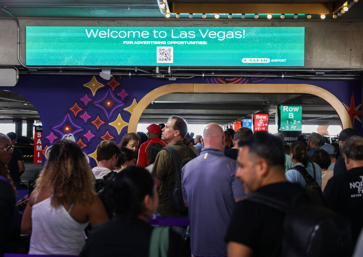 People pass new displays aimed at promoting tourism at the rideshare area at Terminal 1 Friday, ...