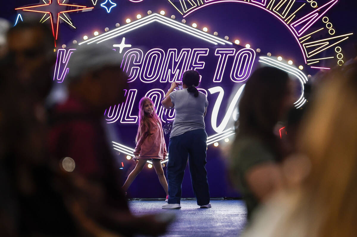 People take photos in front of new displays aimed at promoting tourism at the rideshare area at ...