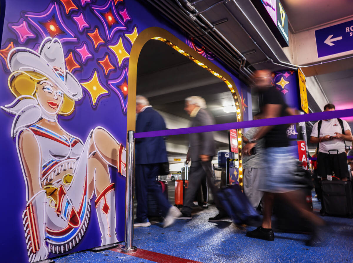 People pass new displays aimed at promoting tourism at the rideshare area at Terminal 1 Friday, ...