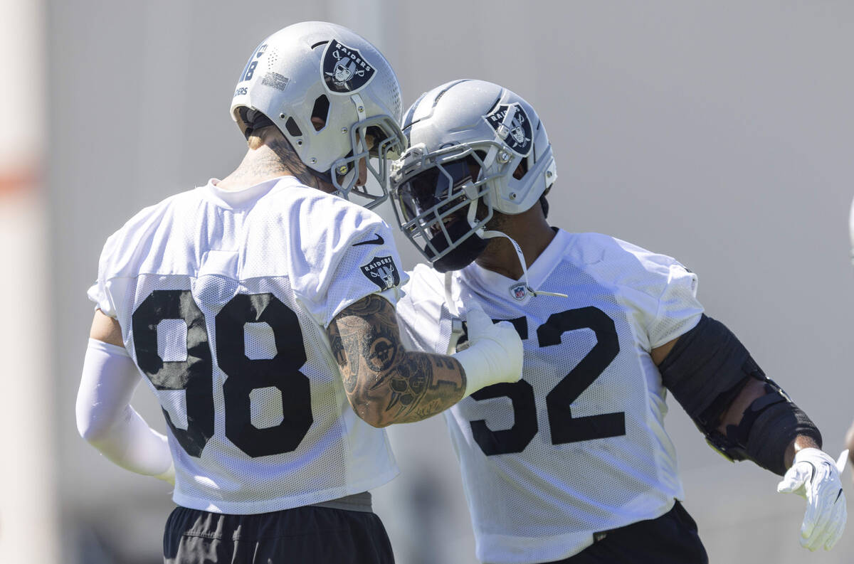 Raiders defensive end Maxx Crosby (98) and linebacker Elandon Roberts (52) greet each other dur ...