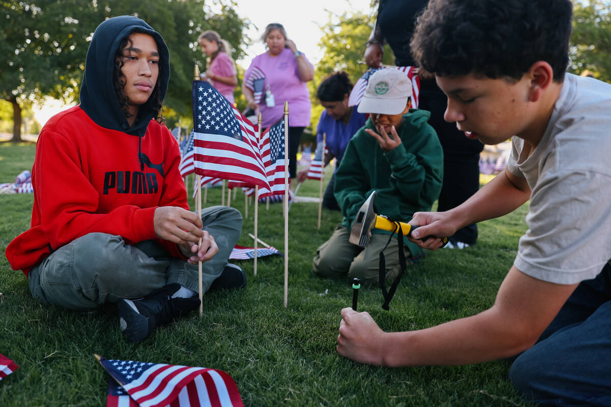 Angel Stefin, left, waits for Colin McPeak, right, to hammer a hole into the ground to plant an ...