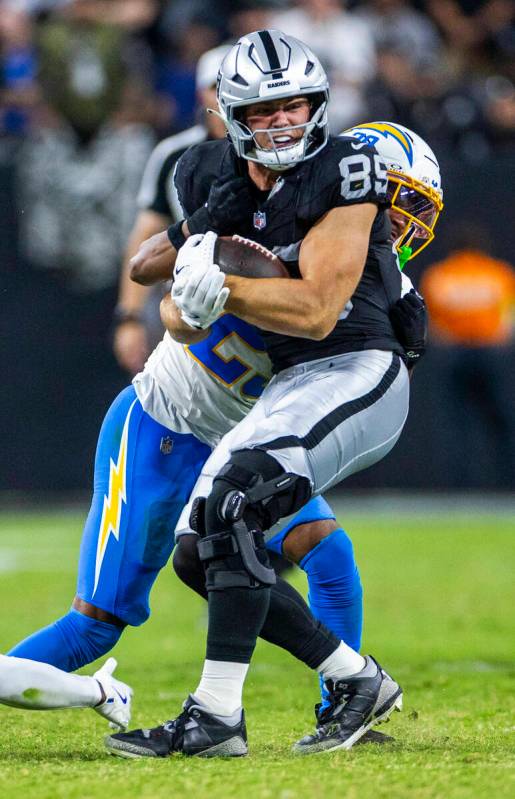 Raiders tight end Brock Bowers (89) takes a shot after a catch by Los Angeles Chargers cornerba ...