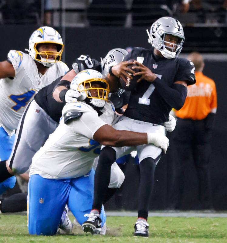 Raiders quarterback Geno Smith (7) is taken down by Los Angeles Chargers defensive tackle Jamar ...