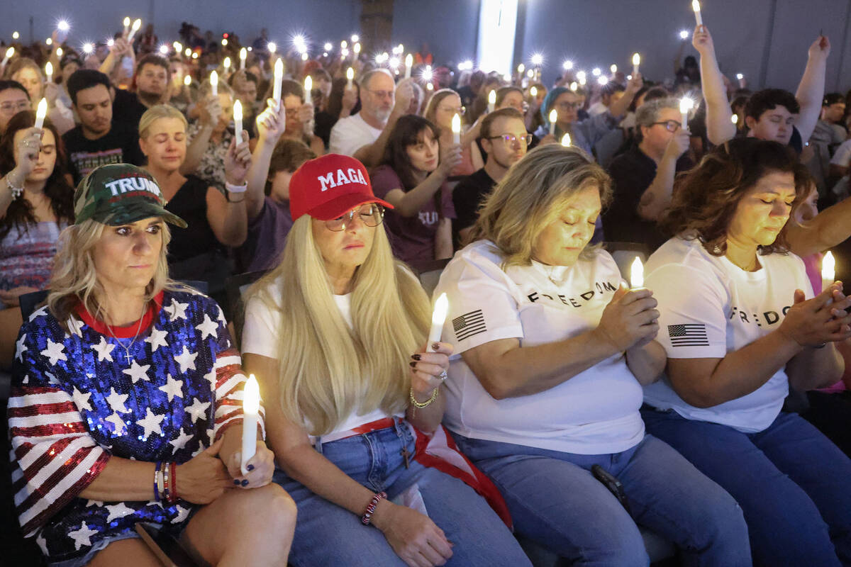 Attendees take a moment of silence while holding candles during a vigil for Charlie Kirk hosted ...