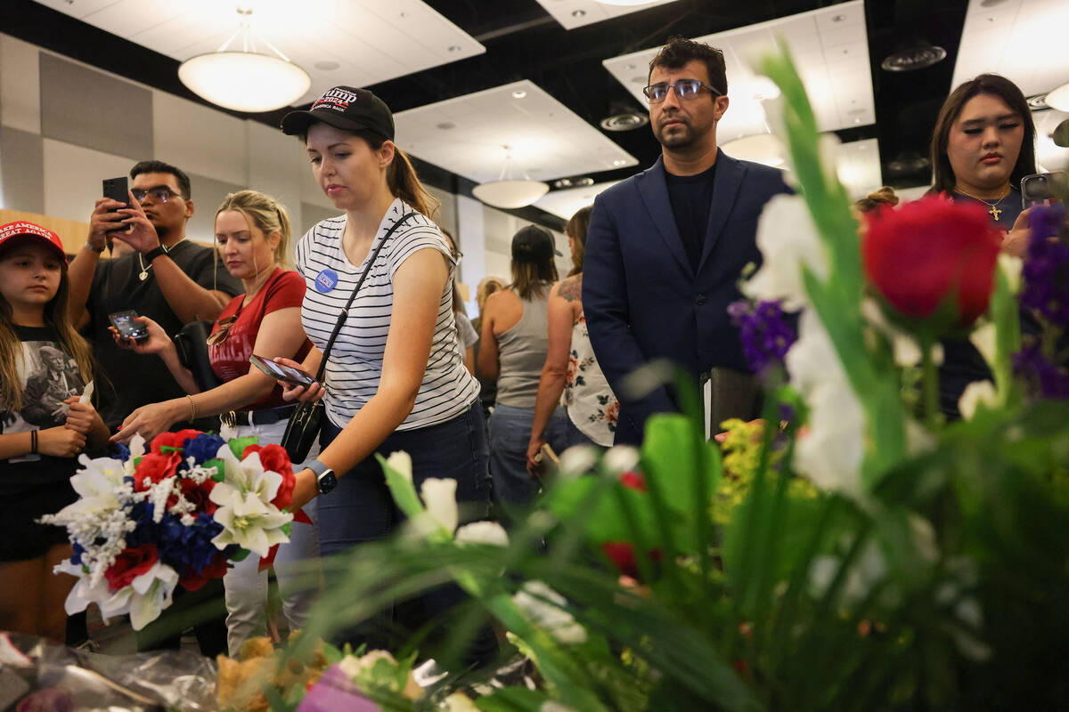 Sage Barlow, front/left, places flowers during a vigil for Charlie Kirk hosted by Turning Point ...