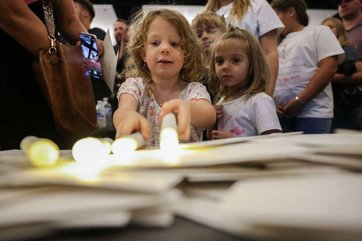 Fiona Bachman, 3, places candles and cards during a vigil for Charlie Kirk hosted by Turning Po ...