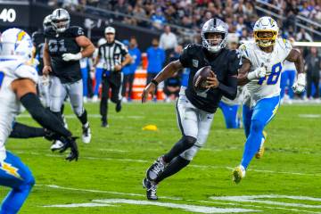 Raiders quarterback Geno Smith (7) looks for more yards after running with the ball pursued by ...
