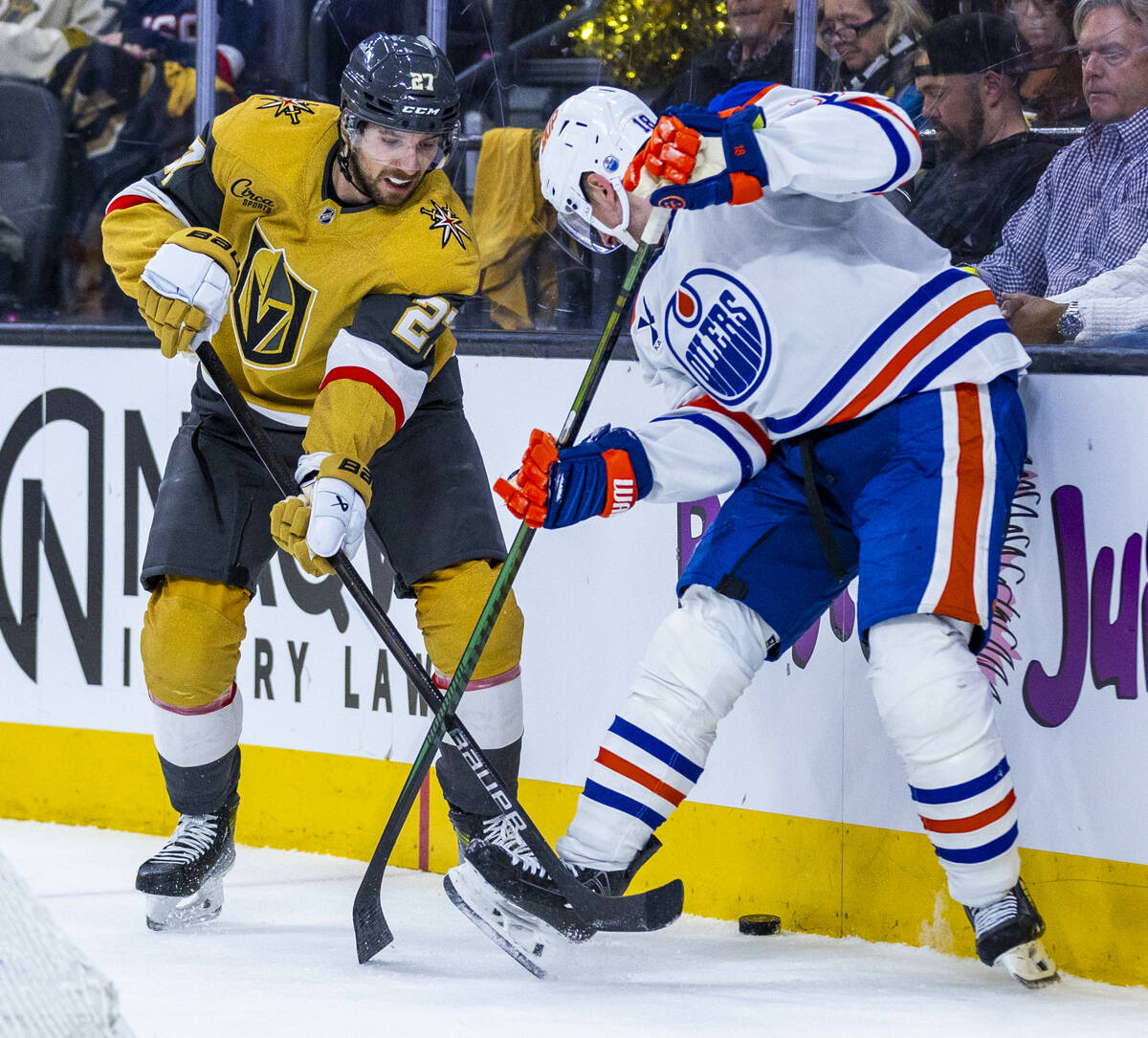 Golden Knights defenseman Shea Theodore (27) and Edmonton Oilers left wing Zach Hyman (18) batt ...