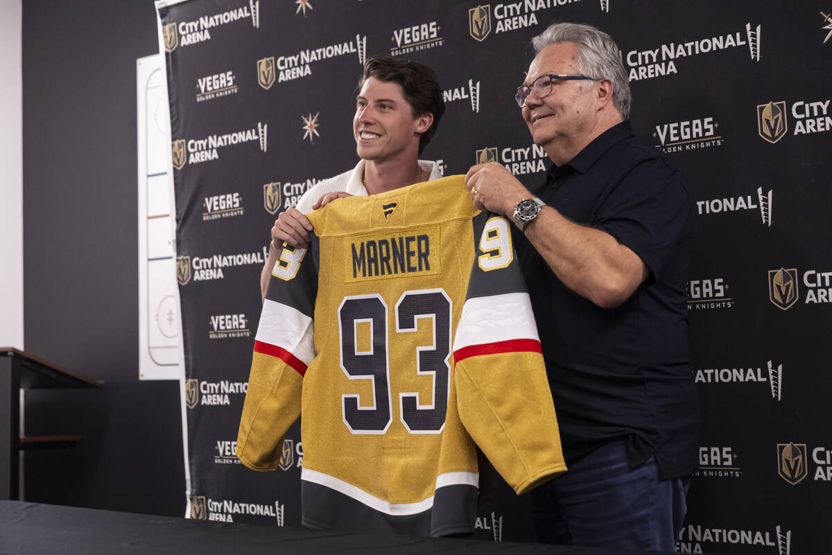 Newly acquired Golden Knights forward Mitch Marner poses with his jersey alongside Golden Knigh ...