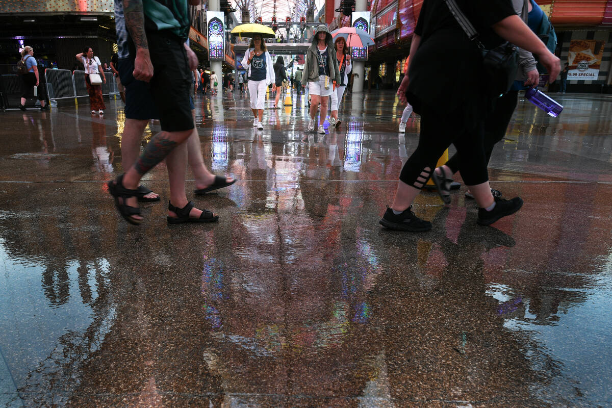 Pedestrians walk under the Fremont Street Experience canopy during a light rain Thursday, Septe ...