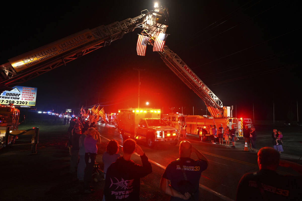 People salute as an ambulance drives past during a procession Wednesday, Sept. 17, 2025, in Spr ...