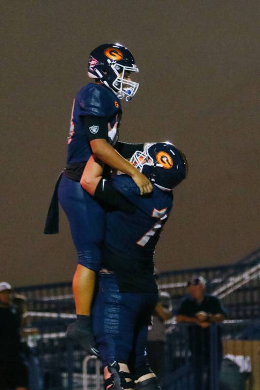 Bishop Gorman defensive back Pesi Silva Jr. (7) lifts up quarterback Maika Eugenio (14) after E ...