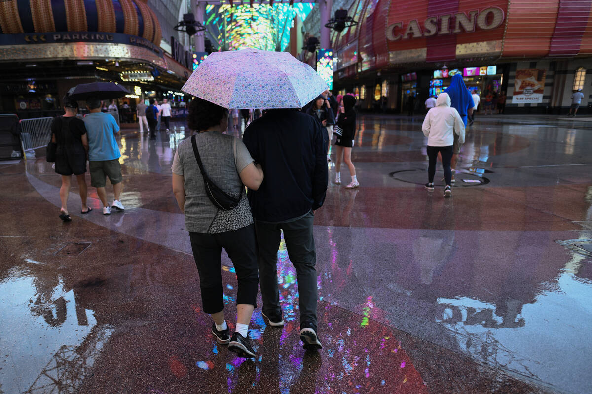 Pedestrians walk under the Fremont Street Experience canopy during a light rain Thursday, Septe ...