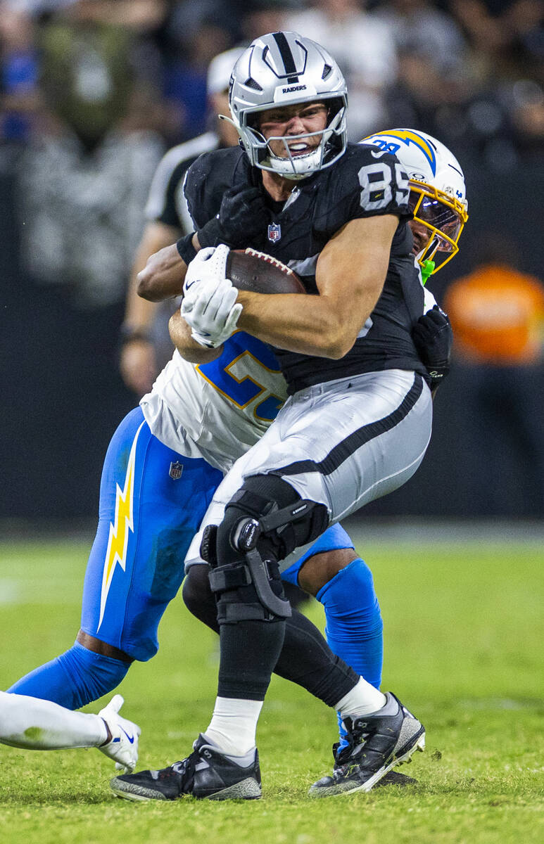 Raiders tight end Brock Bowers (89) takes a shot after a catch by Los Angeles Chargers cornerba ...