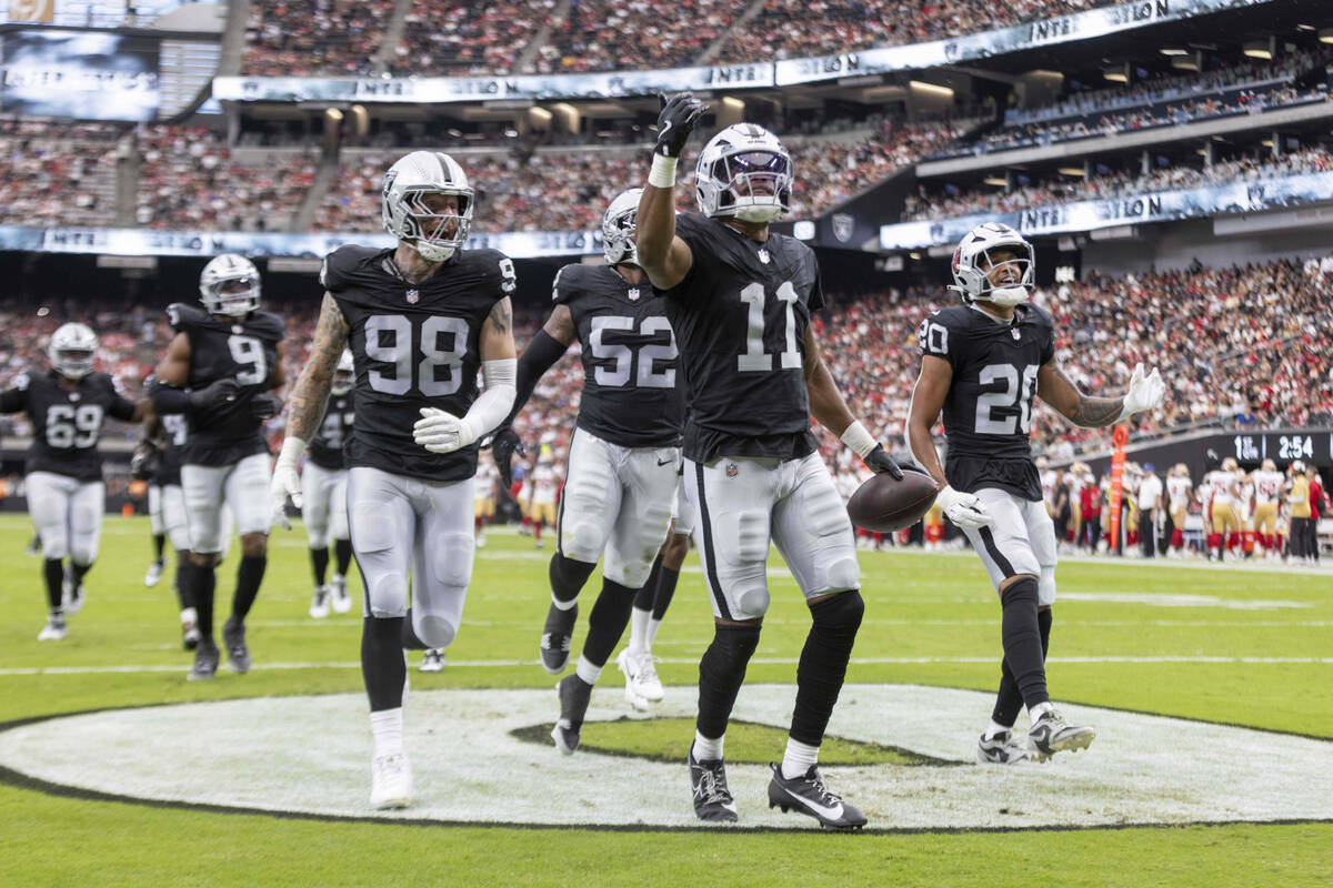 Raiders safety Jeremy Chinn (11) celebrates his interception with defensive end Maxx Crosby (98 ...