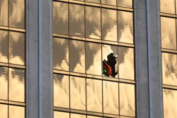 A window, apparently damaged by gunfire, is removed by workers on the west side of W Las Vegas ...