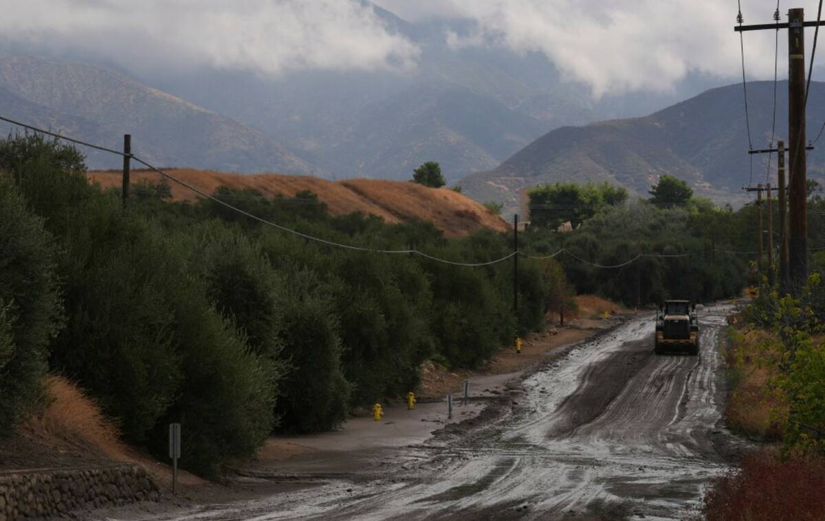 Workers clean up the damage caused by mudslides after storms in Yucaipa, Calif., Friday, Sept. ...