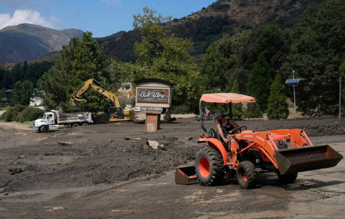 Workers clean up damage from mudslides after storms in Yucaipa, Calif., Friday, Sept. 19, 2025. ...