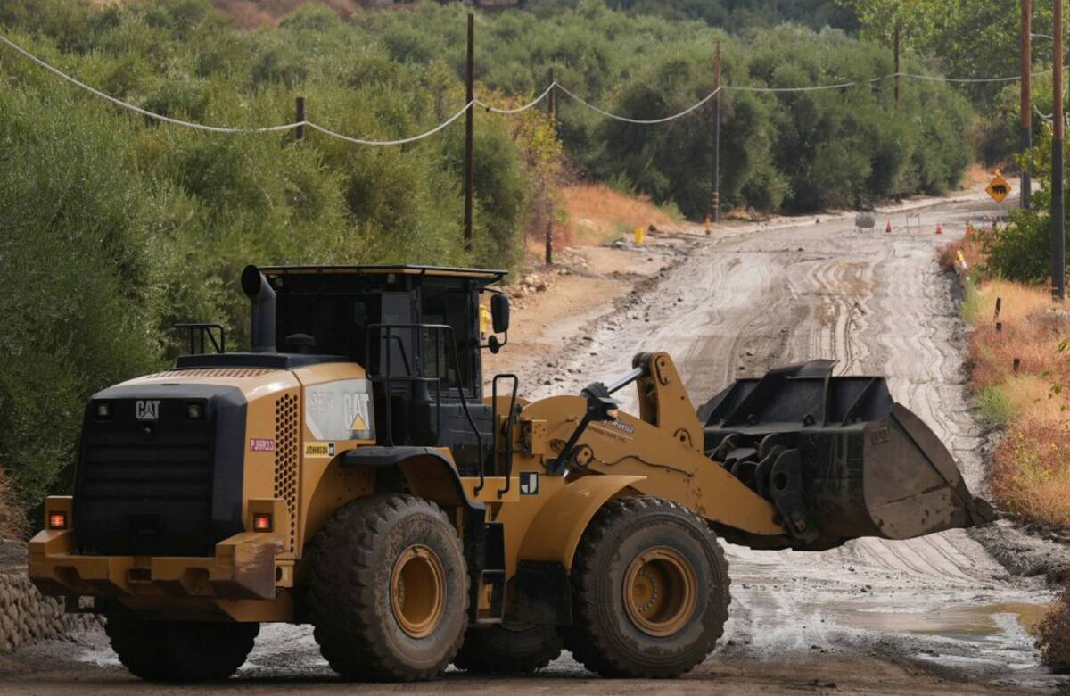 Workers clean up the damage caused by mudslides after storms in Yucaipa, Calif., Friday, Sept. ...