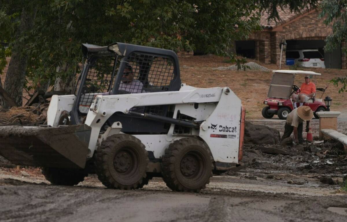 Workers and residents clean up the damage caused by mudslides after storms in Yucaipa, Calif., ...