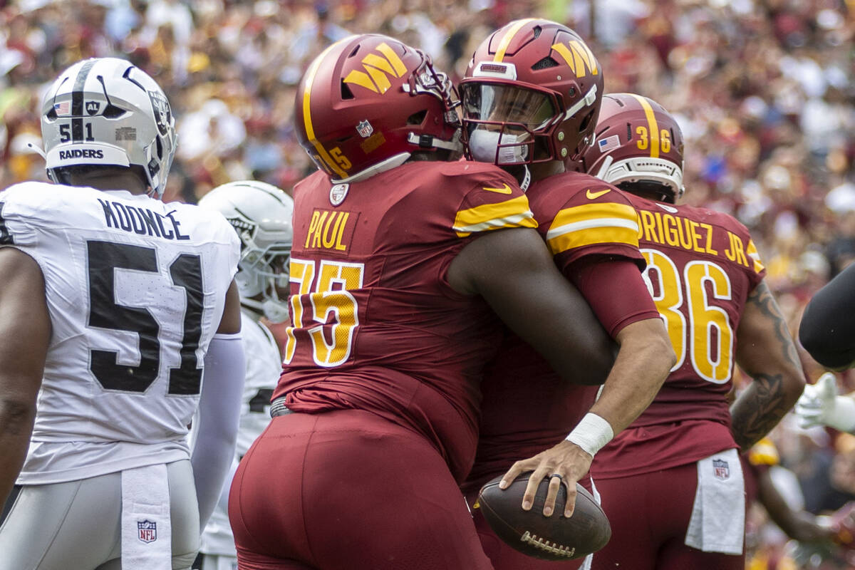 Washington Commanders guard Chris Paul (75) hugs quarterback Marcus Mariota (8) after he scores ...