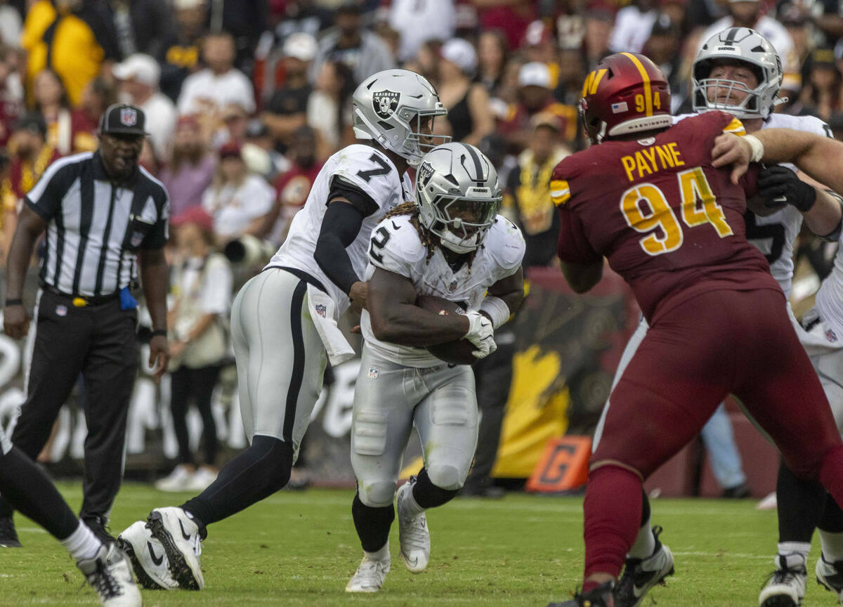 After a handoff from Raiders quarterback Geno Smith (7), running back Ashton Jeanty (2) works f ...