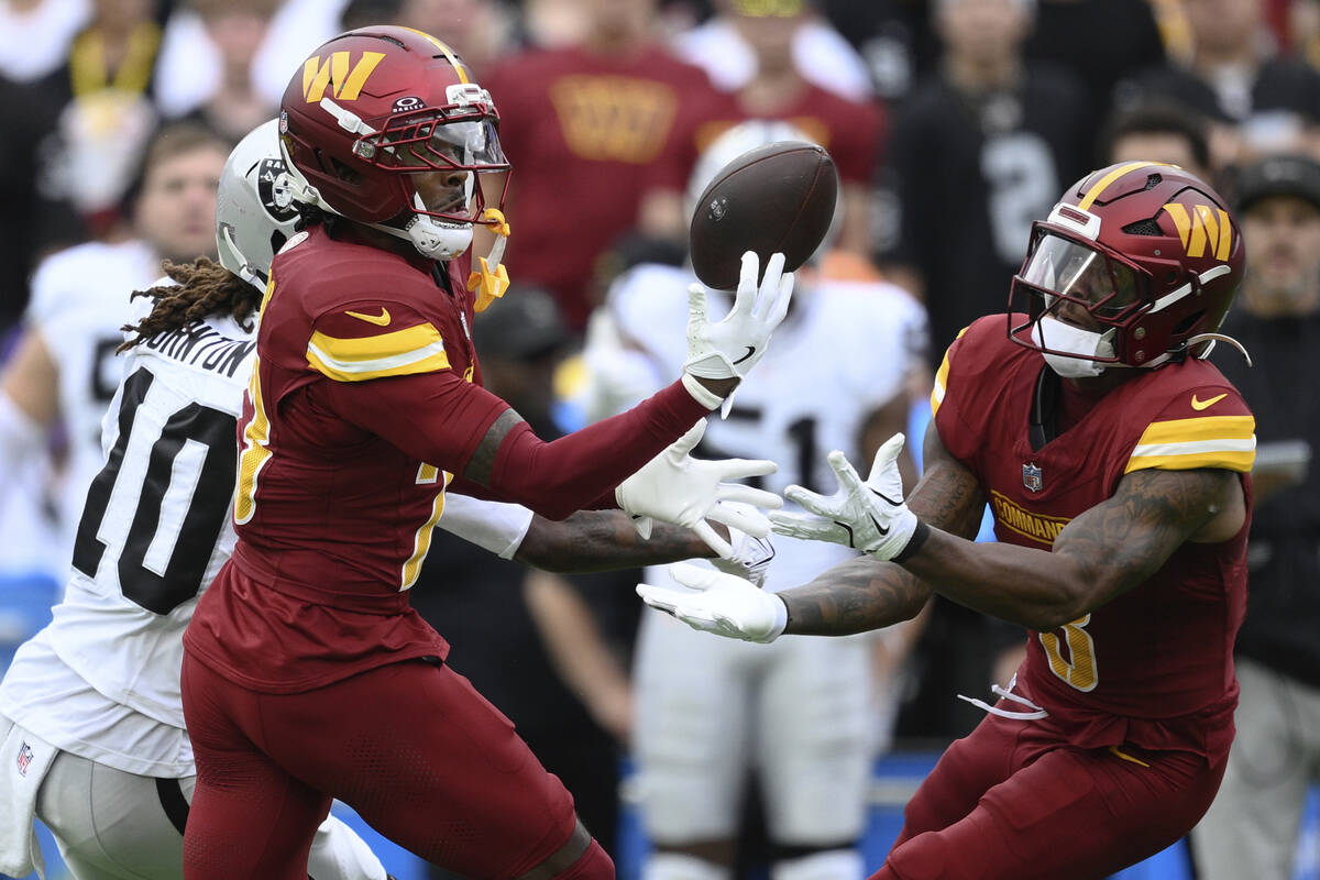 Washington Commanders cornerback Trey Amos (23) and safety Will Harris (3) try to get the ball ...