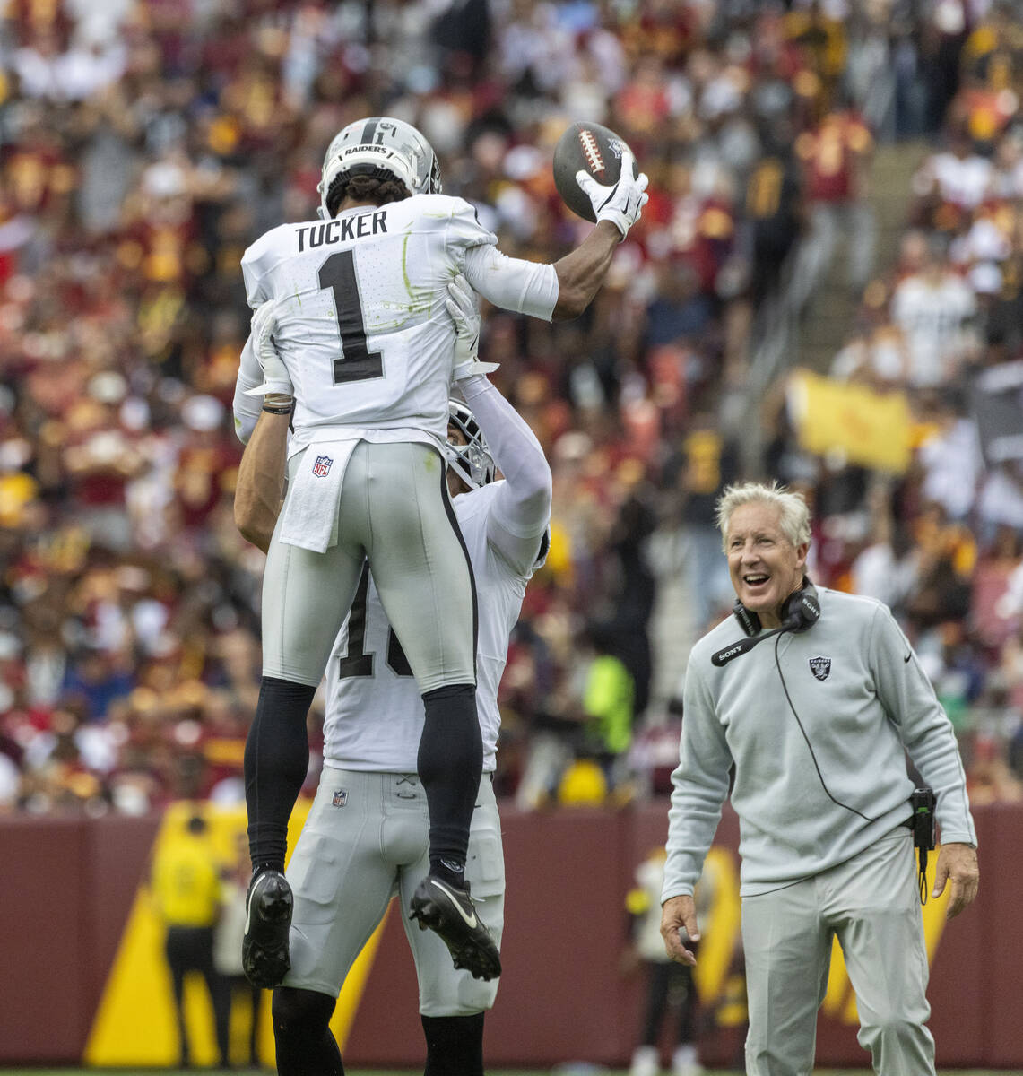 Raiders head coach Pete Carroll looks on smiling as wide receiver Jack Bech (18) lifts wide rec ...