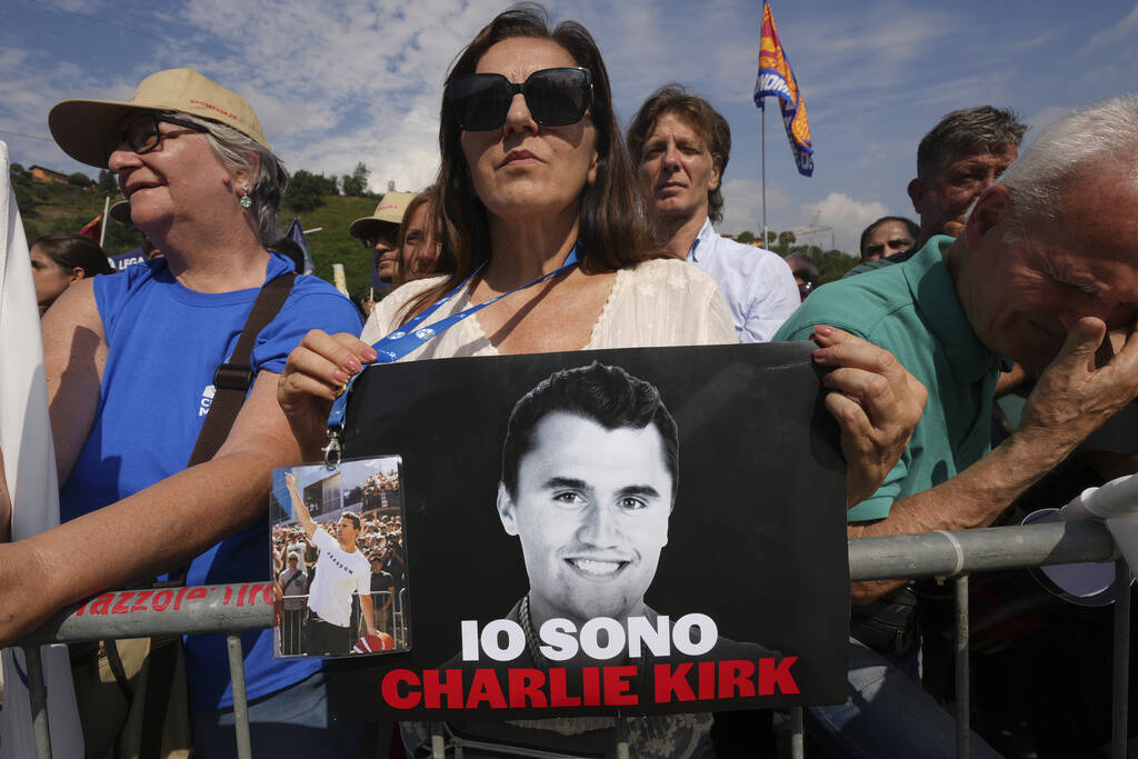 A woman holds a photo of Charlie Kirk that reads: "I am Charlie Kirk", during the Lea ...