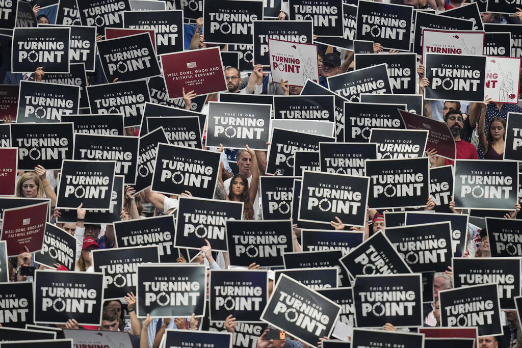 People hold up signs during a memorial for conservative activist Charlie Kirk, Sunday, Sept. 21 ...