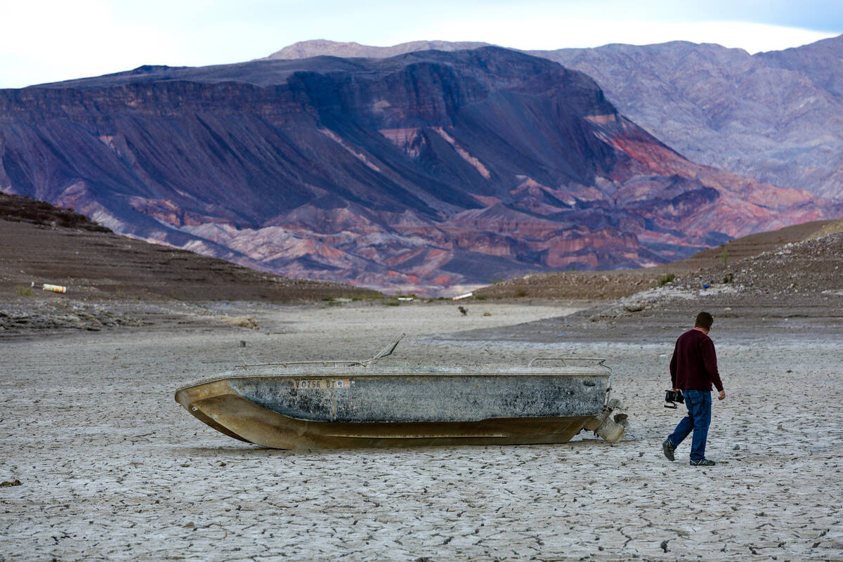 A visitor checks out an old boat left behind as the waterline continues to recede near the clos ...