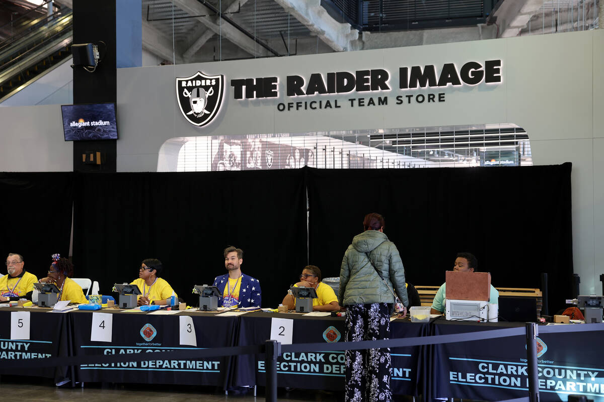 Poll workers help people check in to vote at Allegiant Stadium in Las Vegas on Nov. 5, 2024. (K ...