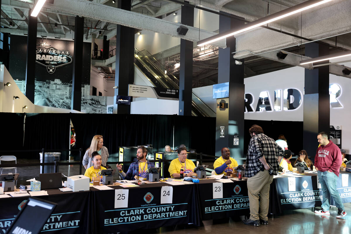 Poll workers help people check in to vote at Allegiant Stadium in Las Vegas on Nov. 5, 2024. (K ...