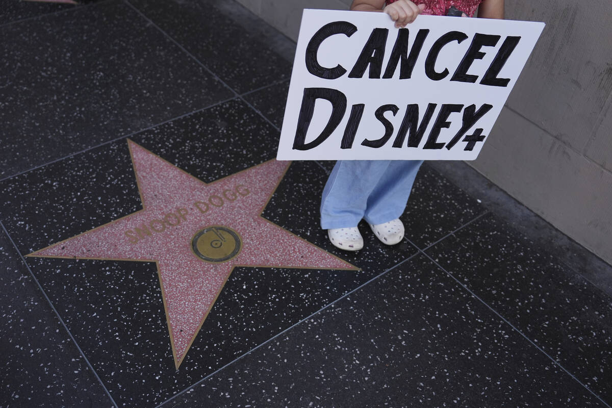 A demonstrator holds a sign reading "CANCEL DISNEY+" outside El Capitan Entertainment ...