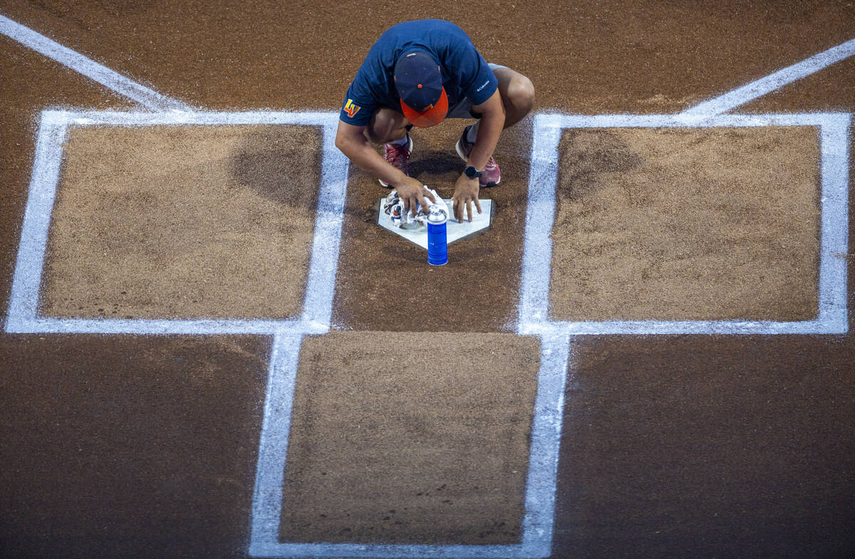 A field crew member cleans home plate as the Aviators will face the Tacoma Rainiers in Game 1 o ...