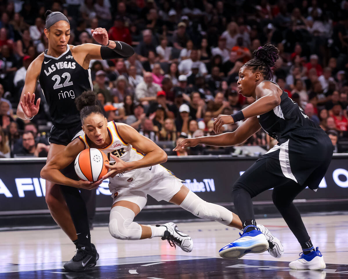 Indiana Fever guard Aerial Powers (23) slips with the ball between Aces center A'ja Wilson ...