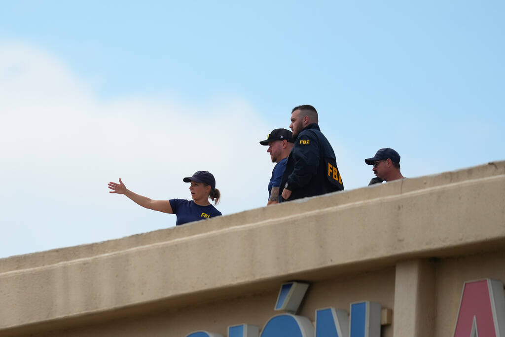 Law enforcement agents look around the roof of an apartment building near the scene of a shooti ...