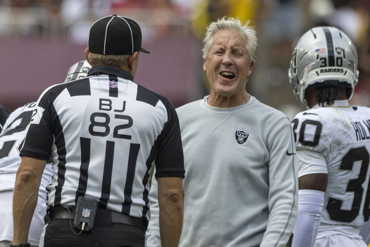 Raiders head coach Pete Carroll reacts during a conversation with back judge Jimmy Russell (82) ...