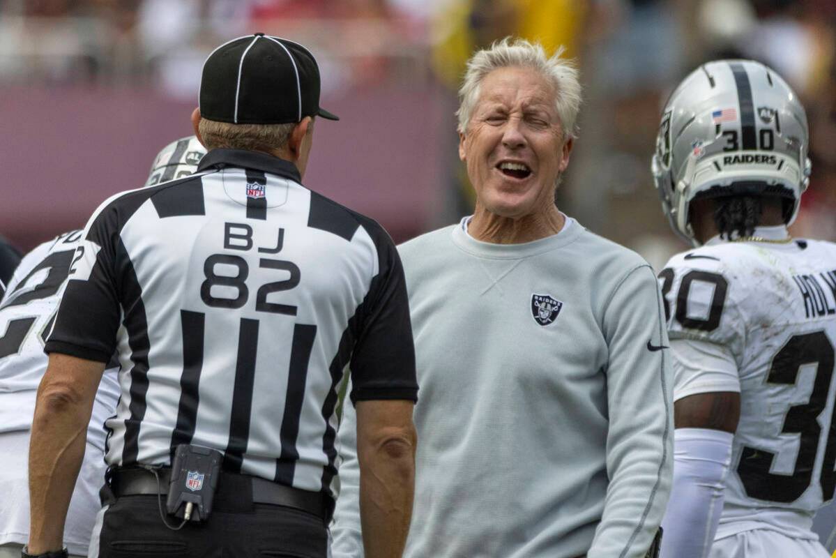 Raiders head coach Pete Carroll reacts during a conversation with back judge Jimmy Russell (82) ...