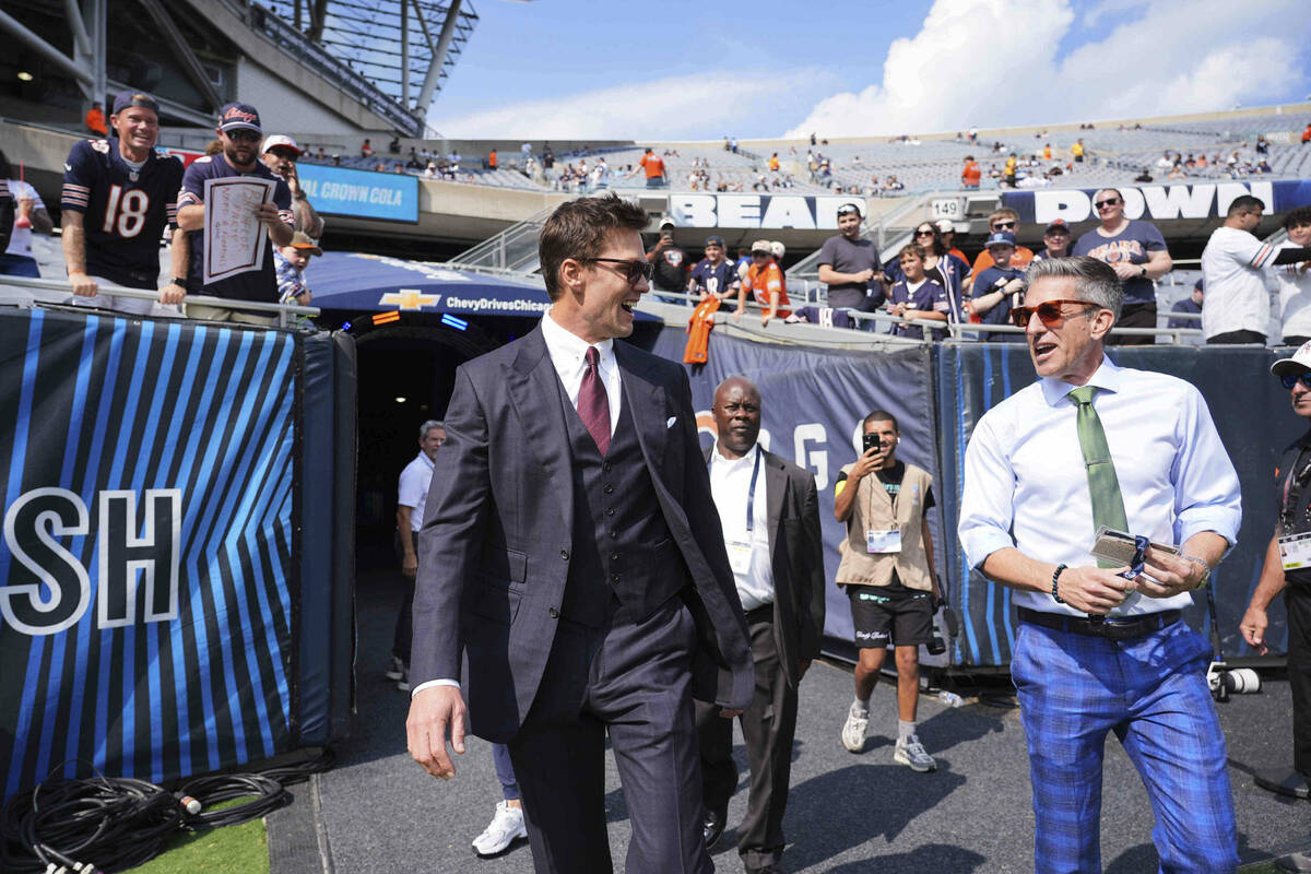 Broadcast analyst Tom Brady, left, walks onto the field with play by play analyst Kevin Burkhar ...