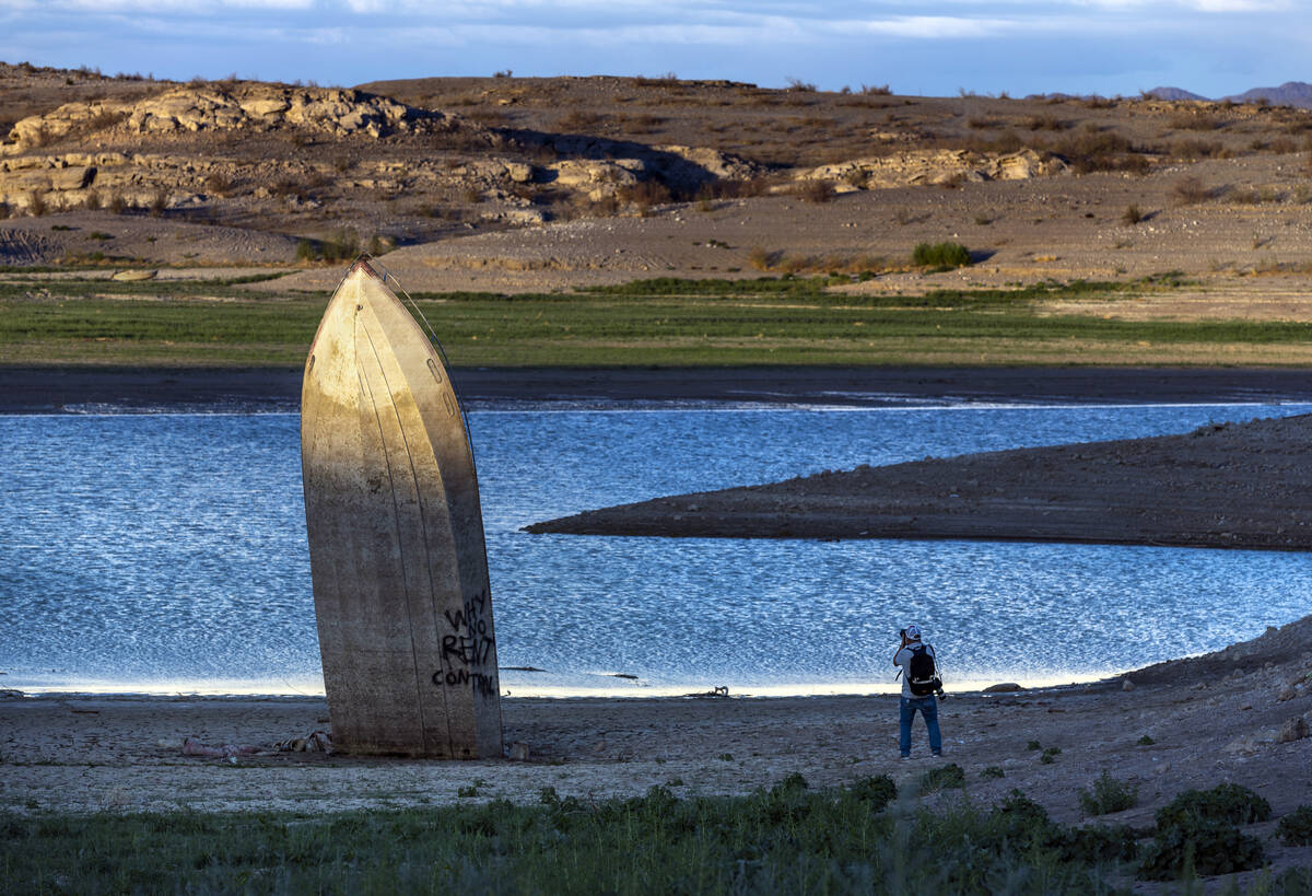 Photographer Mario Tama makes images as the late daylight illuminates a boat stuck straight up ...