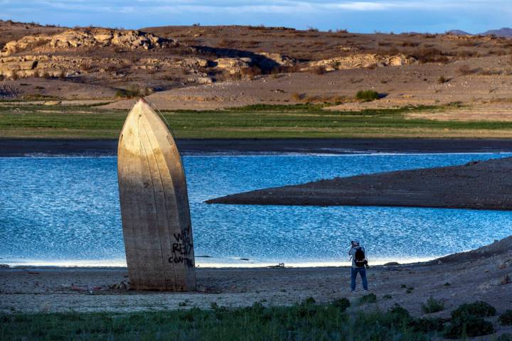 Photographer Mario Tama makes images as the late daylight illuminates a boat stuck straight up ...