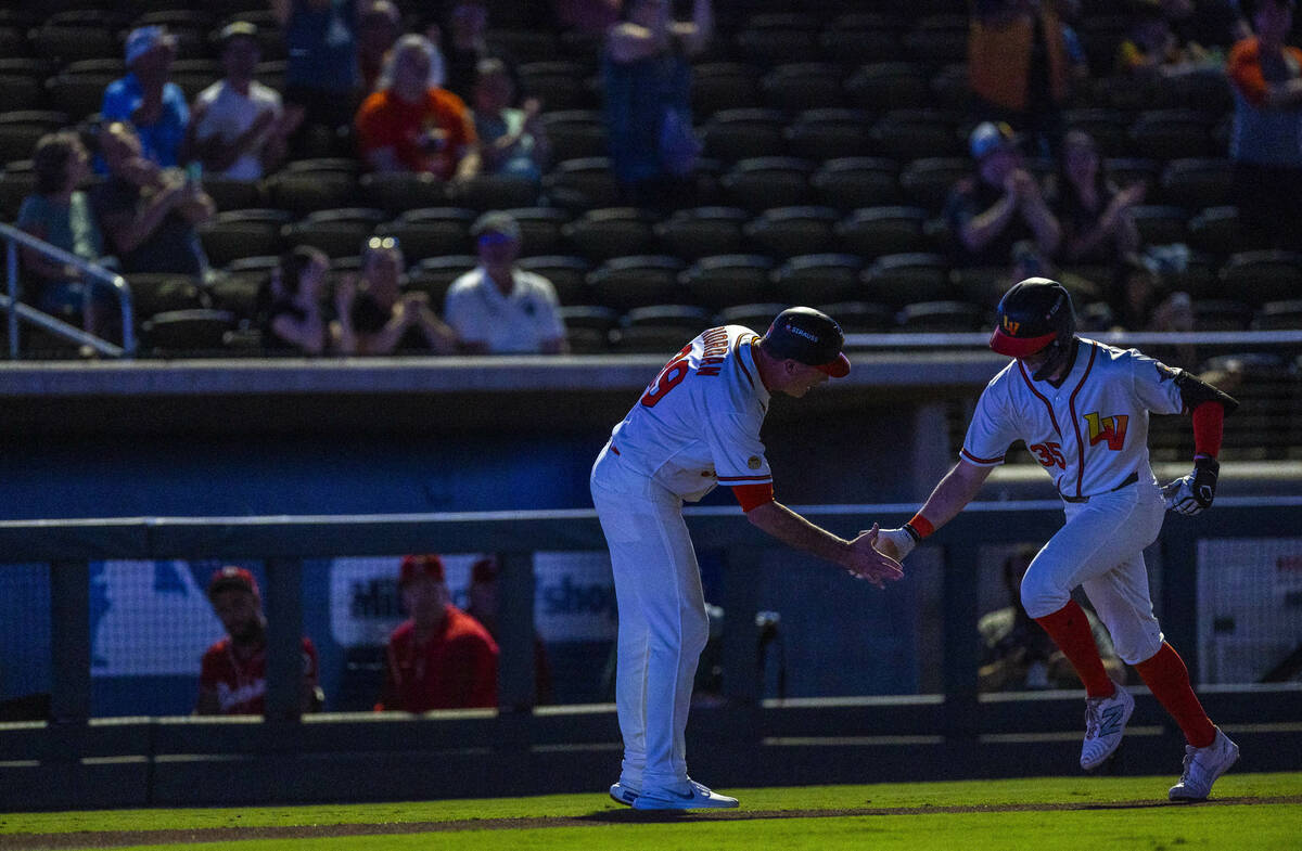 Aviators manager Fran Riordan greets outfielder Ryan Lasko (35) in the dark at third base after ...