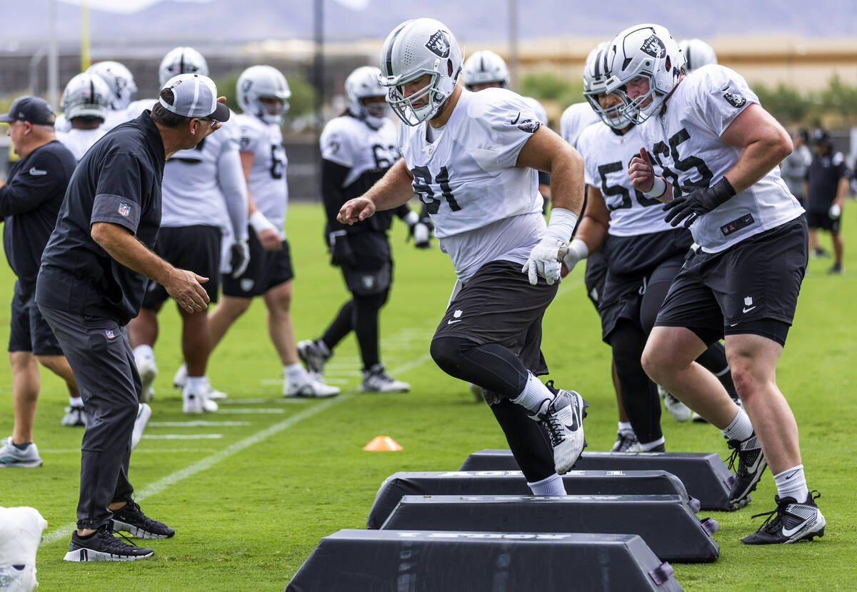 Raiders guards Jordan Meredith (61) and Alex Cappa (65) join others in a warm up drill during p ...