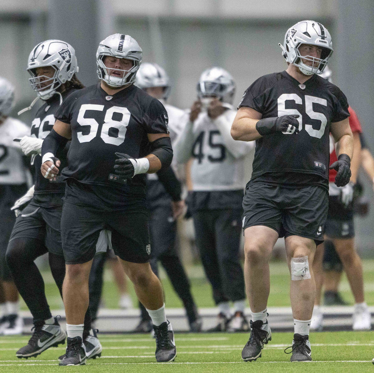 Raiders offensive linemen Jackson Powers-Johnson (58) and Alex Cappa (65) jog on the field duri ...