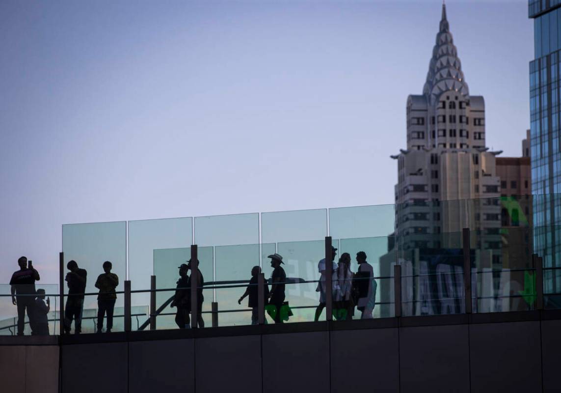 People cross a pedestrian bridge along the Las Vegas Strip during Labor Day weekend on Sunday, ...