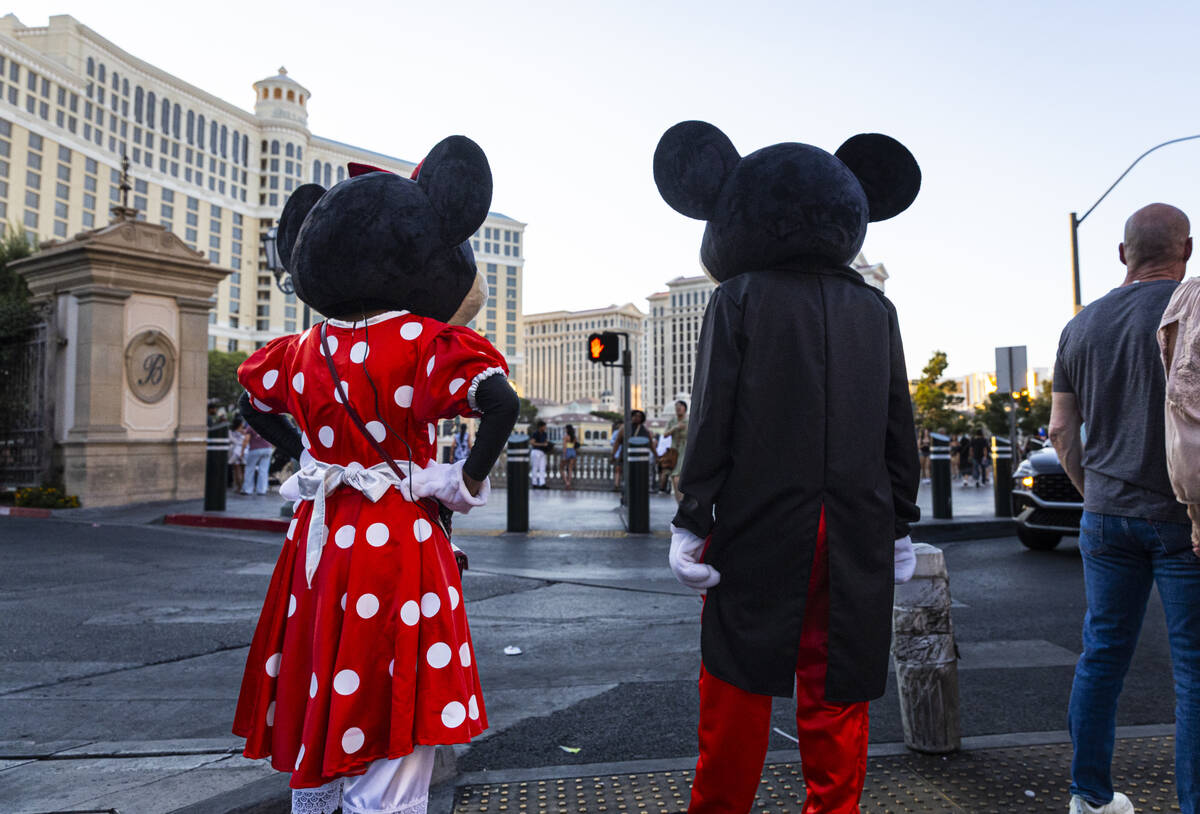 Street performers dressed as Mickey and Minnie Mouse wait for a crosswalk light along the Las V ...
