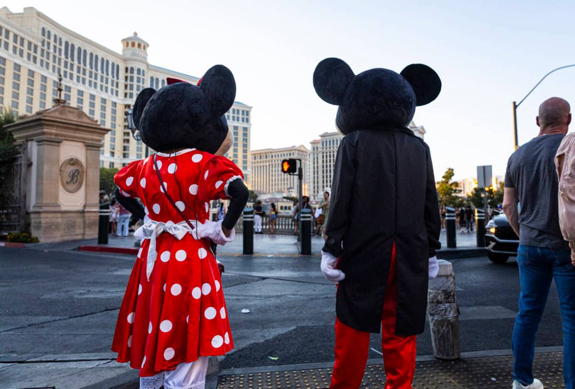 Street performers dressed as Mickey and Minnie Mouse wait for a crosswalk light along the Las V ...